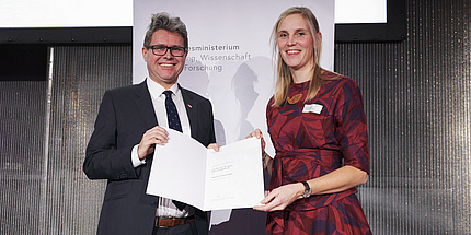 A man and a woman hold a certificate in their hands. 