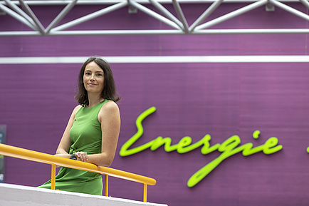 A young woman in a green dress looks into the camera