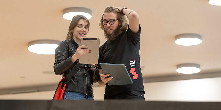 Studentin mit Tablet und Student mit Unterlagen