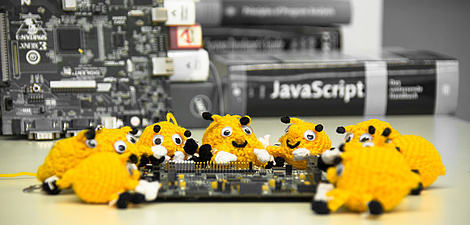 About ten hand-sized, crocheted beetle-like objects are draped around a circuit board.