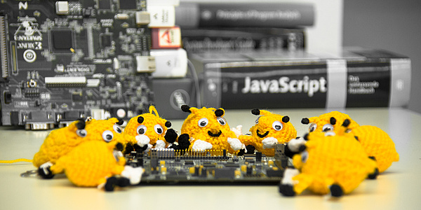 About ten hand-sized, crocheted beetle-like objects are draped around a circuit board.