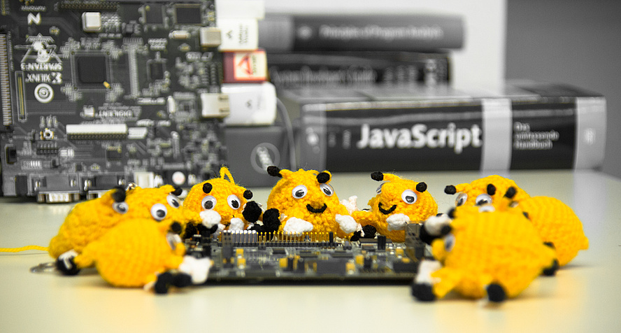 About ten hand-sized, crocheted beetle-like objects are draped around a circuit board.