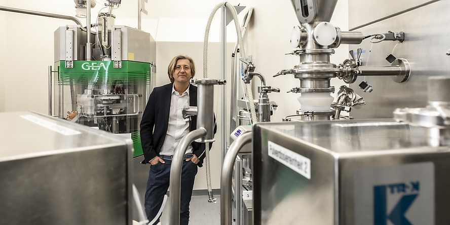 A man stands between silver machinery