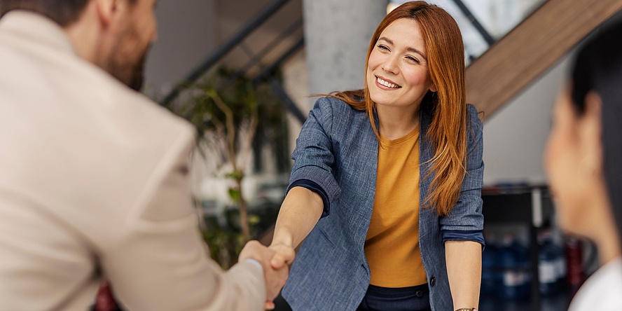 Young woman shaking hands with a man.