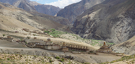 Auf einer Hochebene stehen mehrere Tempelanlagen, im Hintergrund hohe Bergketten.
