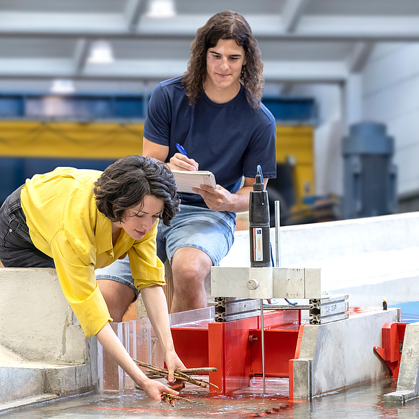 Zwei Studierende mit Wasserbaumodellversuch.