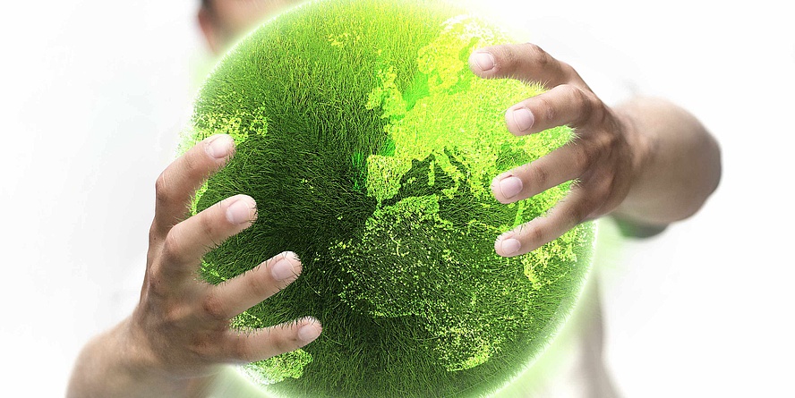 Zwei Hände halten einen grafisch bearbeiteten Erdball, der vollkommen grün bewachsen ist. Die Kontinente sind erkennbar.