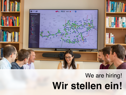 Das Team des IEE sitzt bei einer Besprechung um einen Tisch. Im Hintergrund ein Bildschirm mit dem Elektrizitätssystem Österreichs.