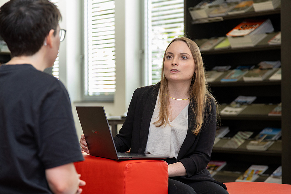Bildquelle: Frankl – TU Graz Eine Frau sitzt vor einem aufgeklappten Laptop, ihr gegenüber sitzt eine weitere Person. Im Hintergrund ist ein Regal mit Zeitschriften.
