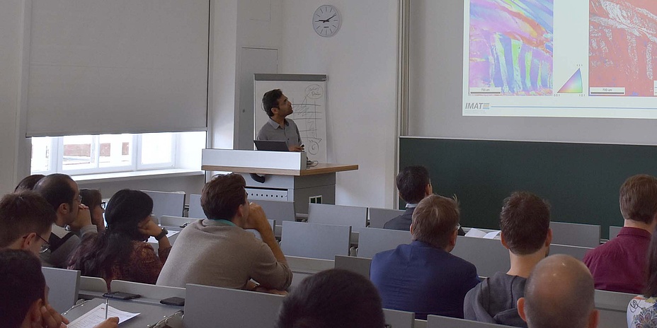 Gastprofessor hält Beamerpräsentation vor Studierenden.