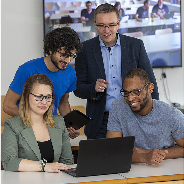 [Translate to Englisch:] Supervisor and students working together on a project 