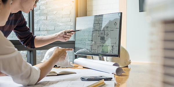 Working desk with a screen and construction plans.