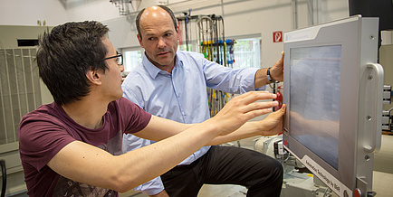 Two men discuss IT-applications in front of a monitor