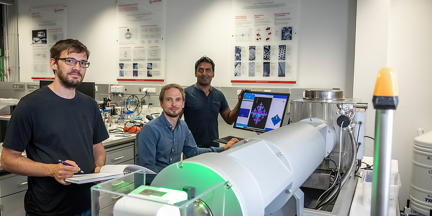 3 men in front of an X-ray measuring machine