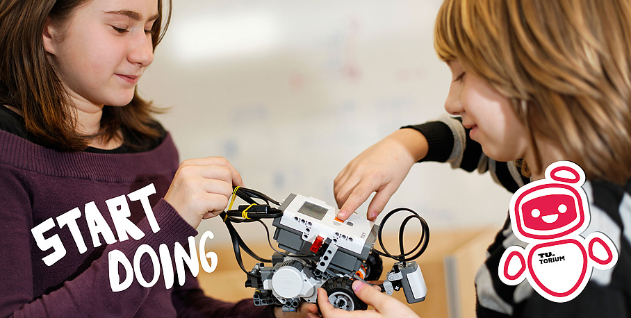 Zwei Kinder arbeiten an einem Roboter.