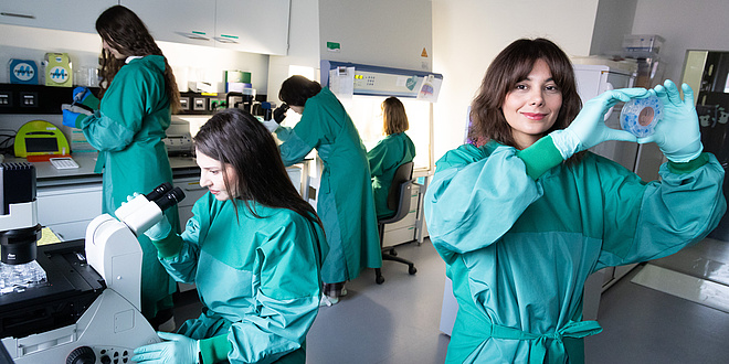 Fünf Forscherinnen in Labormänteln bei der Arbeit im Labor.