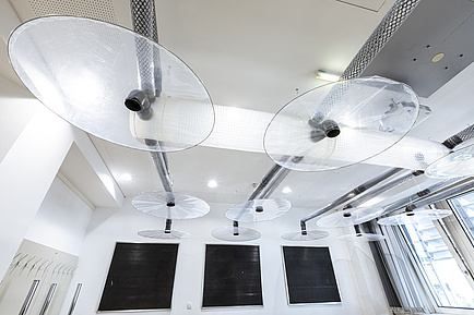 View of a ceiling with pipes and transparent plate-like objects.