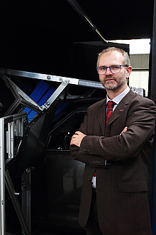 TU Graz scientist in front of a driving simulator