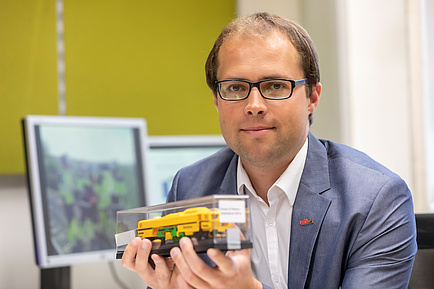 TU Graz researchers with model of a tamping machine