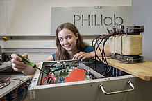 Eine Frau arbeitet mit einem Schraubendreher an elektronischen Steckverbindungen.