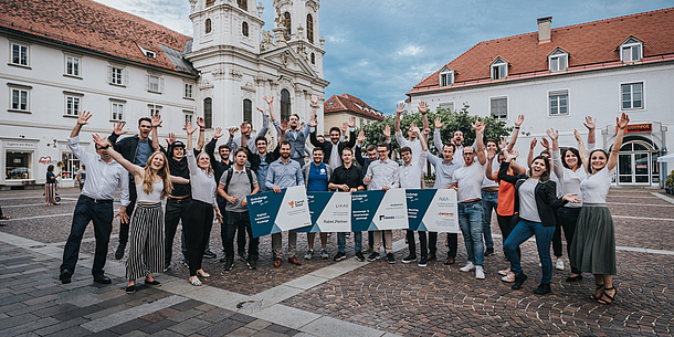 Young people stand cheering on a square in a city.