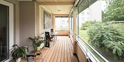 A bright wooden room with large windows facing a park.