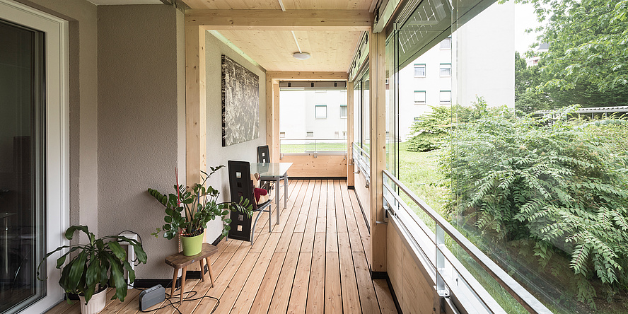 A bright wooden room with large windows facing a park.