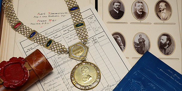 Archive materials: documents, a document roll and a chain of office. Source: Herbst – TU Graz