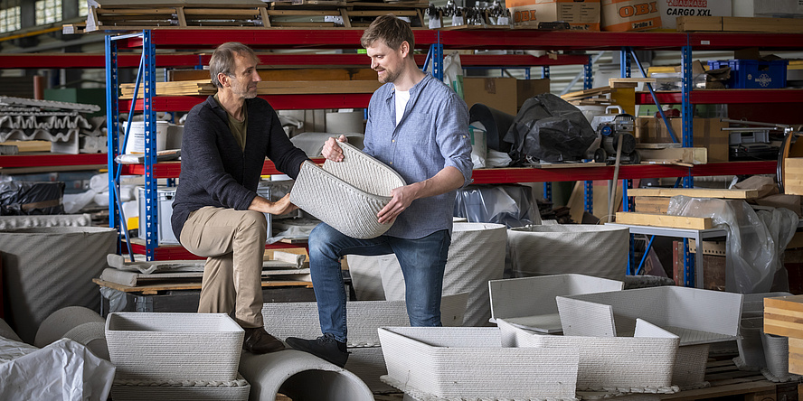 Two men are holding a concrete object and talking.