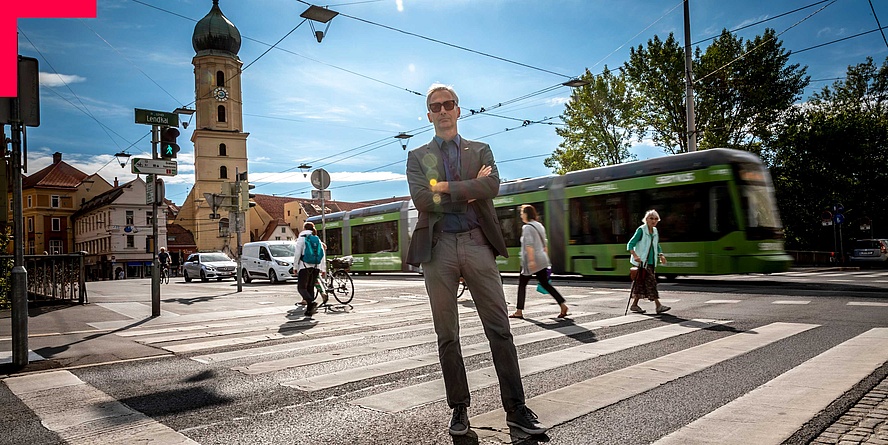 Prof. Römer stands with crossed arms on a crosswalk