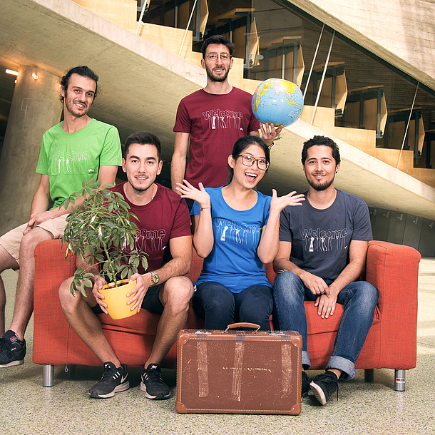 Fünf junge Menschen mit Globus, Topfpflanze und Koffer.