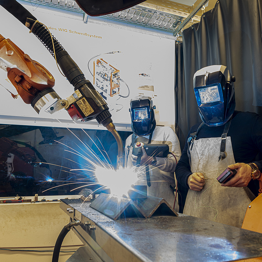 2 people with a welding robot