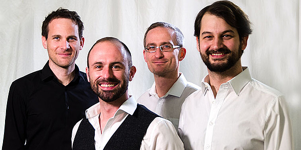 Four men with white and black shirts on a white background.