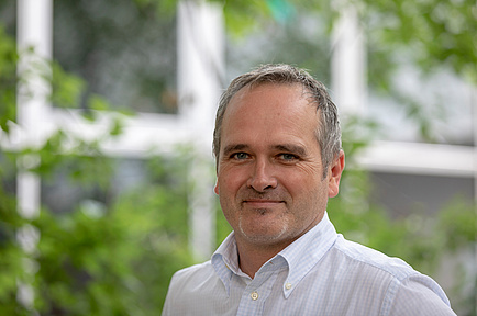 TU Graz researcher in front of a window facade