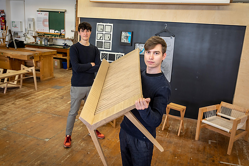 Zwei Architekturstudierende mit Bank in der TU Graz-Holzwerkstatt