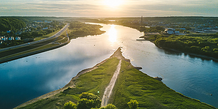 A fork in the river with green banks, houses and a road