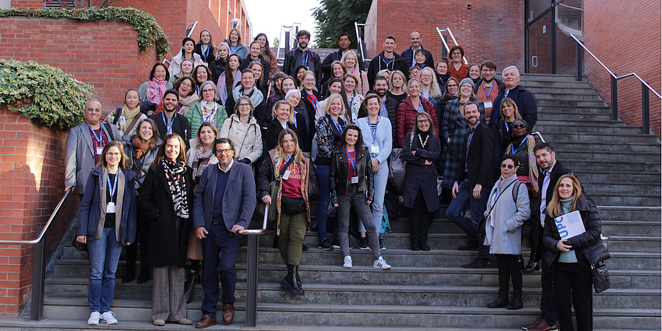 A group of people stand outside on a staircase and smile at the camera.