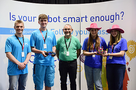 Five people stand next to each other and look into the camera.