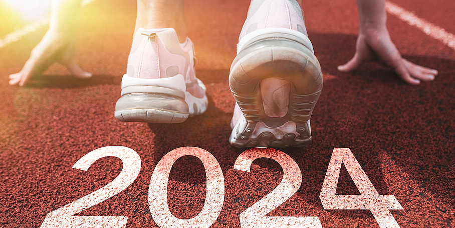 Weibliche Füße und Hände auf einer Sportlaufbahn bereit für den Start mit der Jahreszahl 2024