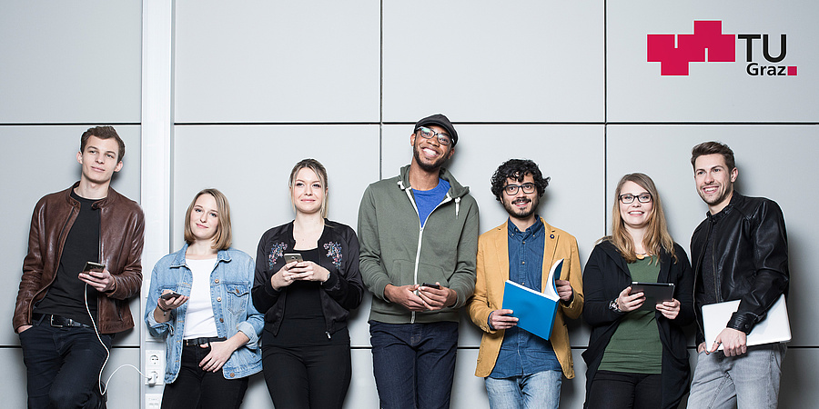7 Studierende stehen vor einer Wand. Sie halten Handys, Notizbuch, Tablet und Laptop in der Hand. Bildquelle: Marija Kanizaj - TU Graz