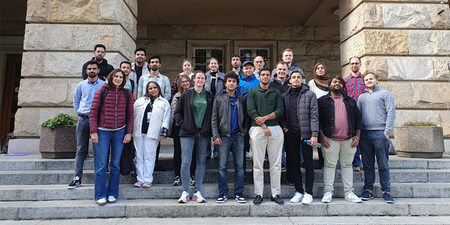 Eine Gruppe Studierender steht auf einer Treppe vor einem historischen Gebäude.