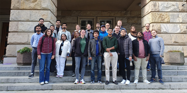 Eine Gruppe Studierender steht auf einer Treppe vor einem historischen Gebäude.