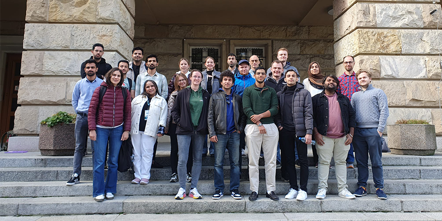Eine Gruppe Studierender steht auf einer Treppe vor einem historischen Gebäude.