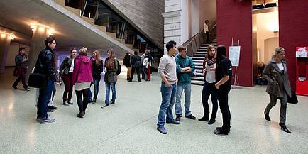 Approx. 15 Studierende in smaller groups in front of Lecture Hall 1 at TU Graz' Campus "Alte Technik".