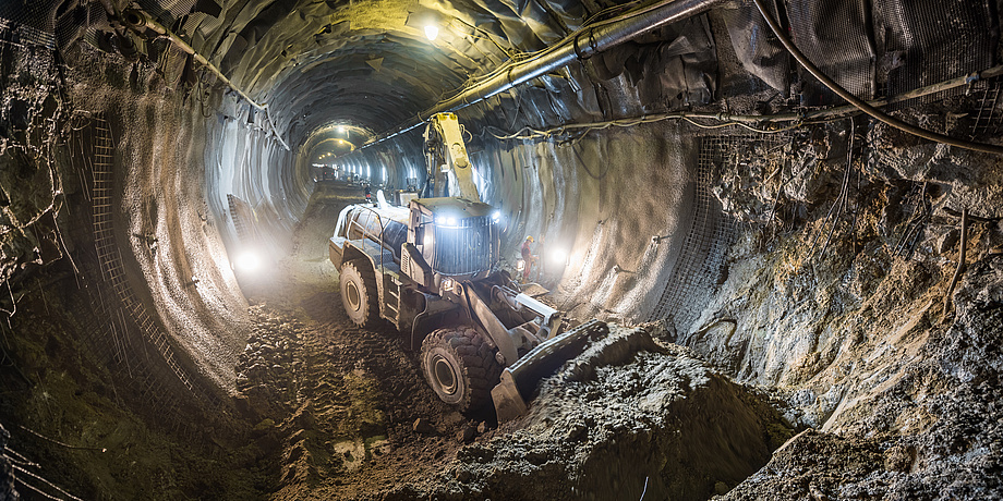 Ein Caterpillar Tunnelbagger schiebt in einem Tunnel Erde beiseite. 