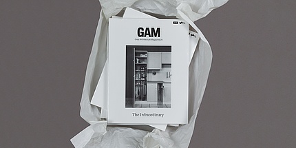 Aufgerissenes Paket mit Zeitschriften mit der Aufschrift "GAM" von oben fotografiert.