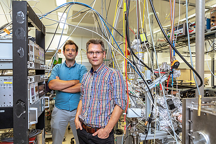 Zwei TU Graz Forscher in einem Physiklabor inmitten von Kabeln und Geräten