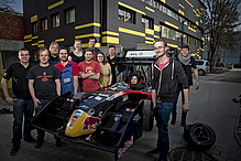 Young people stand around a racing car.