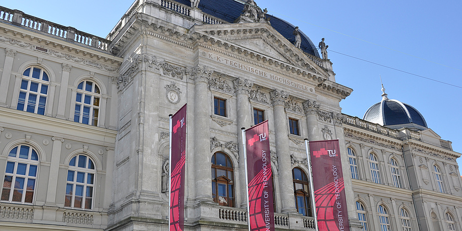 Historical building of TU Graz with three TU Graz flags