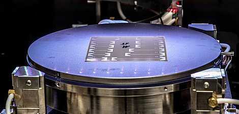 Ein dünnes, silbriges Objekt auf einer kreisrunden, beleuchteten Unterlage.